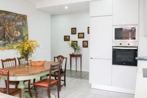 Cozy kitchen and dining area in Aquarela apartment with rustic wooden table, vintage chairs, and modern built-in appliances